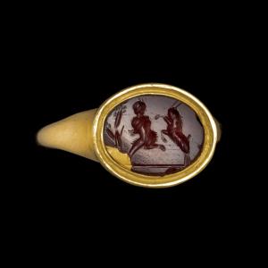 A Gold Ring Set With A Roman Carnelian Intaglio. Pan Fighting A Goat.