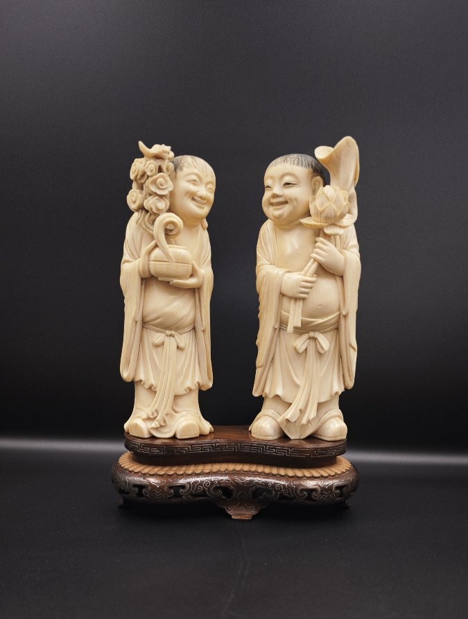 Coppia di sculture in avorio raffiguranti gemelli Hehe con fiori in mano, Cina dinastia Qing