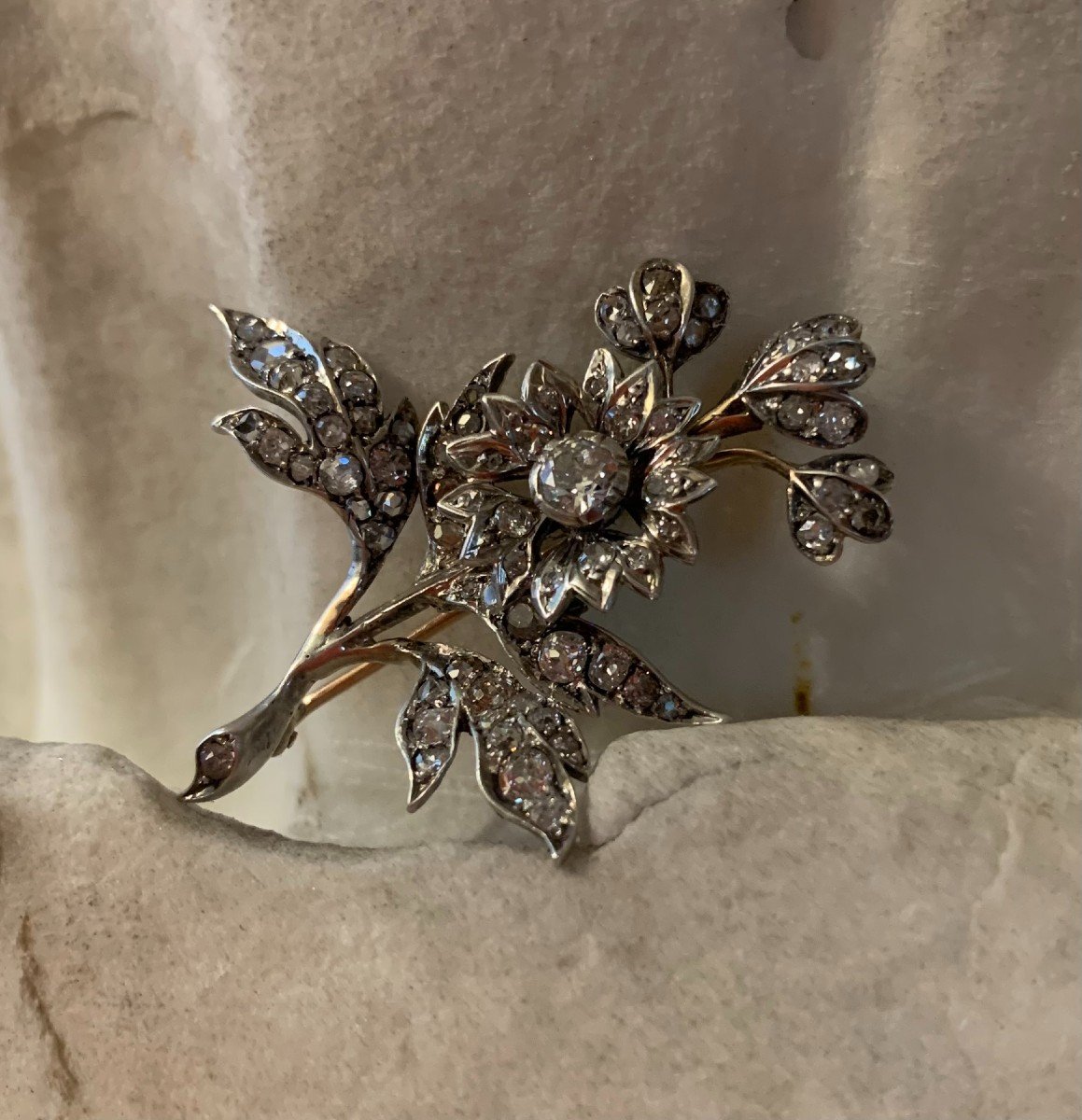 Una spilla a forma di un rametto con i fiori con diamanti antichi oro e argento. XIX secolo.