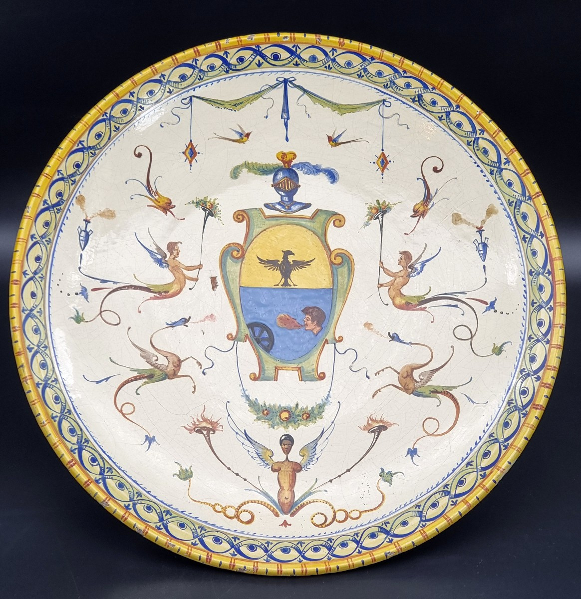 Grande piatto da parata in maiolica decorata a grottesche, con stemma nobiliare – Italia centra