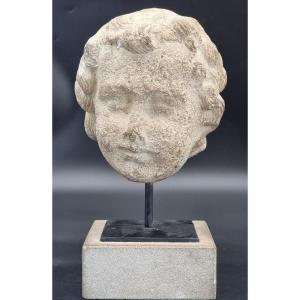 Testa di putto in pietra calcarea, su base moderna