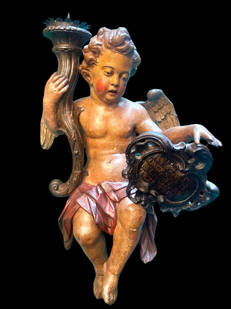 Scultura in legno policromo raffigurante un angelo con torcia portacandela e scudo rocaille 