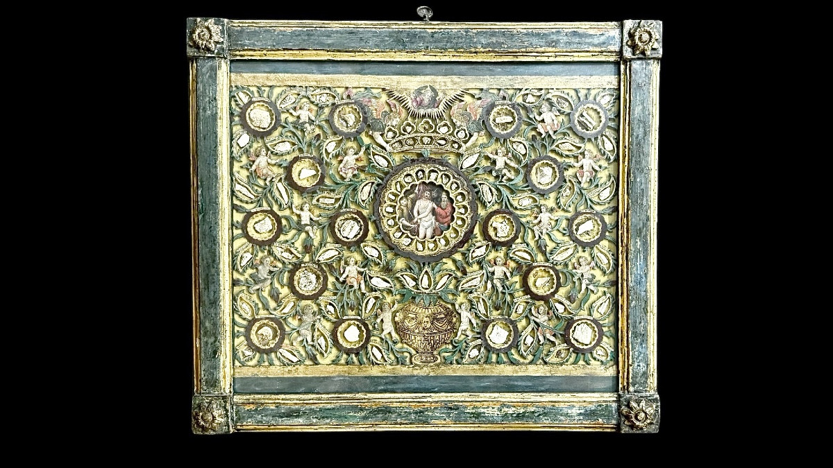 Quadro reliquiario con composizione in legno traforato in rilievo con putti e motivi vegetali.