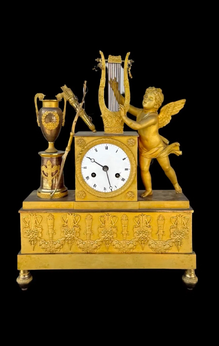 Orologio in bronzo dorato al mercurio con raffigurazione di cupido che suona la lira. 