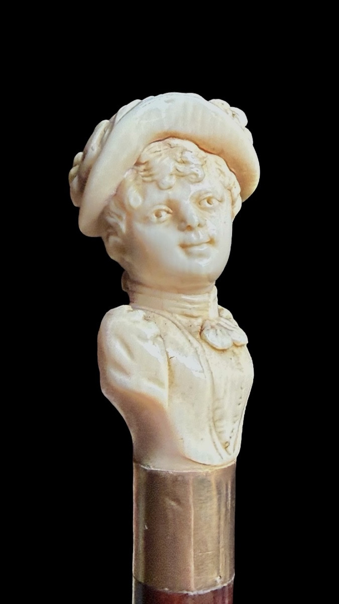 Bastone con pomolo in avorio raffigurante busto femminile con cappello. 