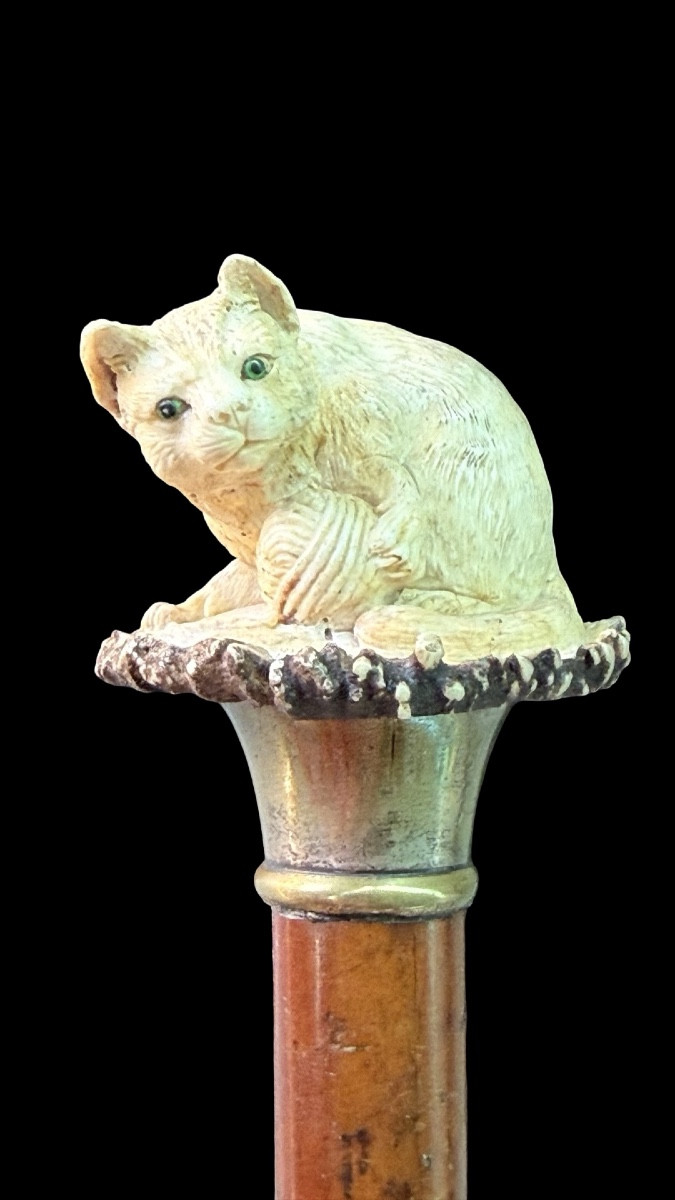 Bastone con pomolo in corno di cervo raffigurante gatto che gioca con gomitolo. 