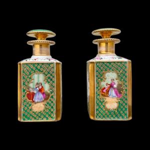Coppia di bottiglie porta profumo in porcellana con figure femminili e decori floreali e oro.