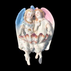 Acquasantiera in porcellana bisquit con due angeli.