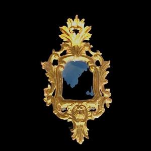 Specchiera in legno scolpito con motivi vegetali, rocaille e foglia oro.Venezia.