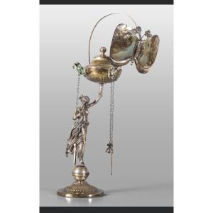 Description Lampada in argento sbalzato raffigurante figura neoclassica con portaluce a forma d