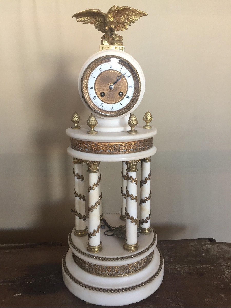 Orologio circolare in marmo bianco, riccamente ornato da bronzi dorati e tipica aquila impero 