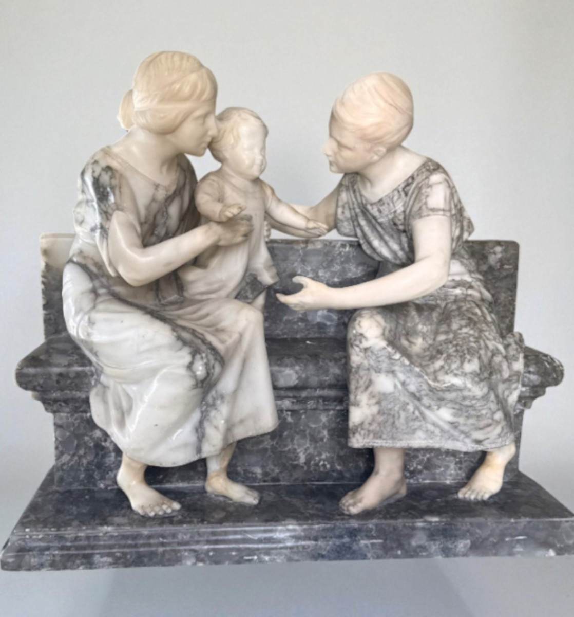 Gruppo Scultoreo coppia di Fanciulli con un bambino in braccio, seduti su una panca, Marmo 