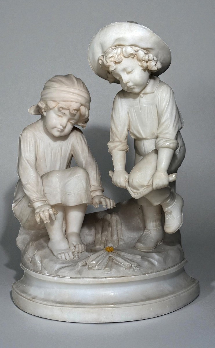 Statua due bambini che si scaldano accanto al fuoco