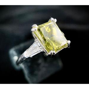 18k White Gold Ring Set With 1 Emerald Cut Yellow Diamond Of +/- 3 Carats And 2 Diamonds