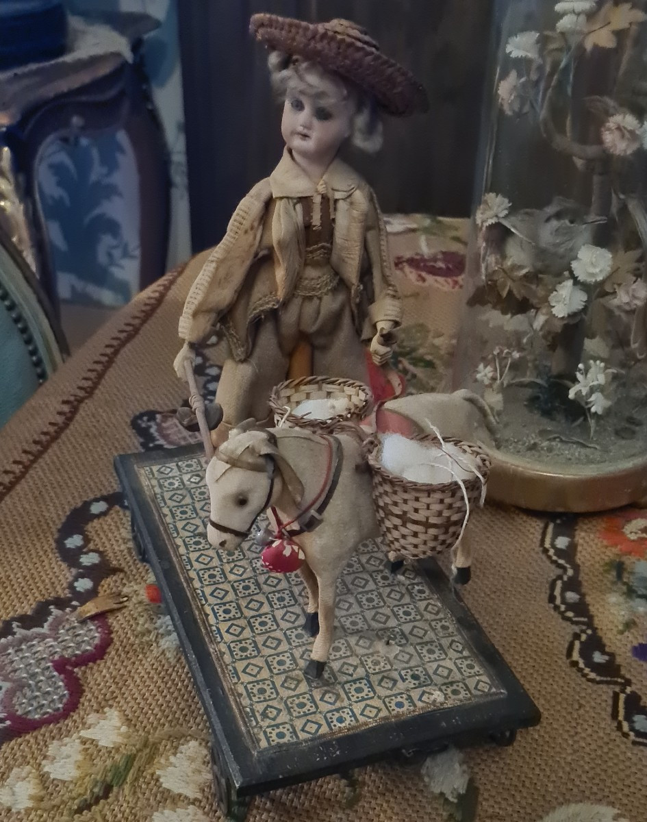 Antico giocattolo con mecanismo. Caretto con asino e bambola di biscuit.