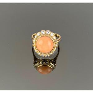 Gold Ring Adorned With A Coral Surrounded By Diamonds