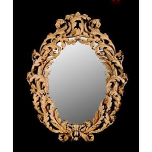 Specchiera ovale con cornice in legno riccamente intagliata e traforata a foglie d'acanto