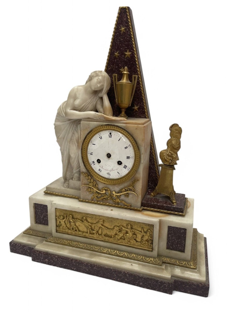 Orologio in marmo e porfido decorato con una vestale in marmo. inizio del XIX secolo