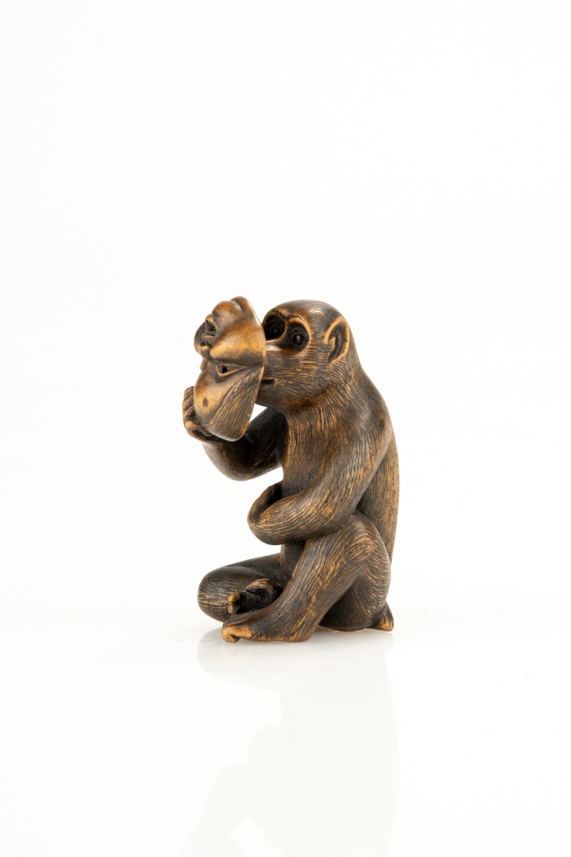 Netsuke in bosso raffigurante una scimmia con la maschera di Okame, firmato Shinzan