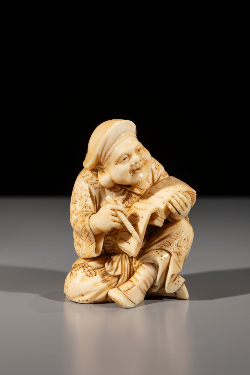 Okimono in avorio raffigurante Daikoku con pennello e libro