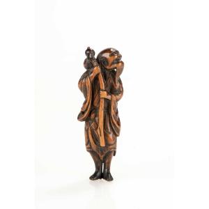 Netsuke in legno di bosso raffigurante un Sennin con bottiglia di sakè