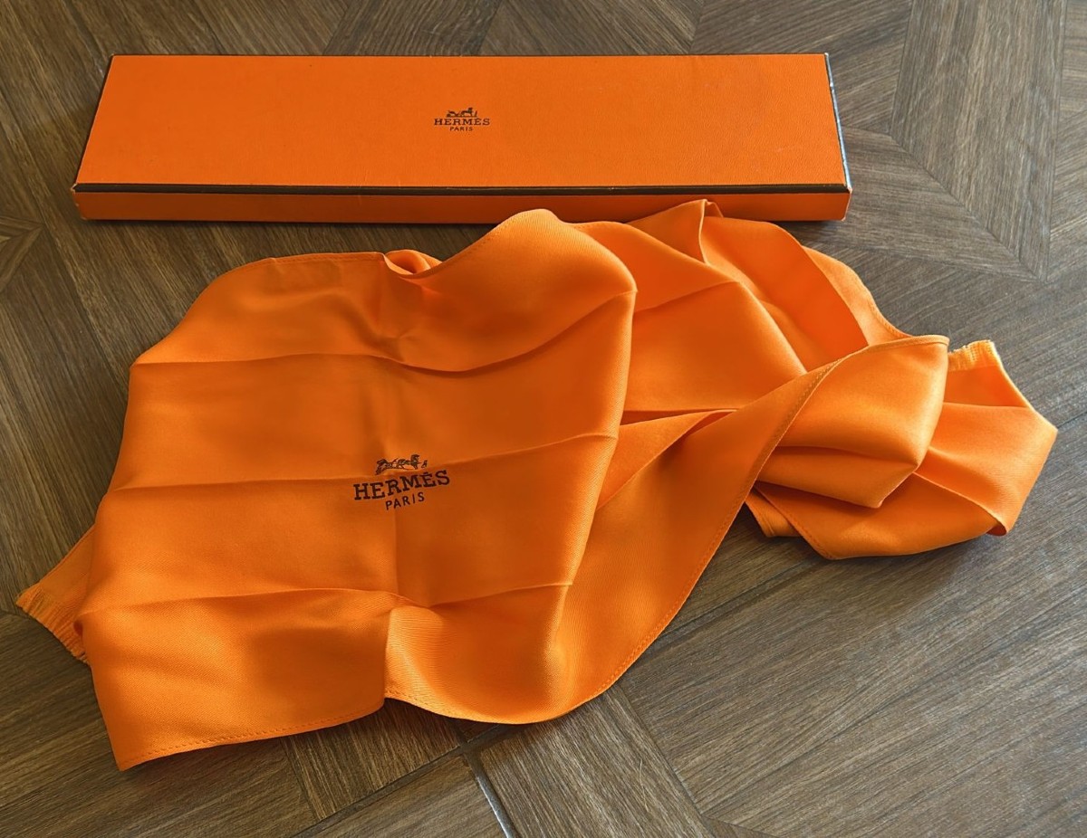 Cravatta foulard Hermès in seta pura nell'iconico colore della maison francese. 