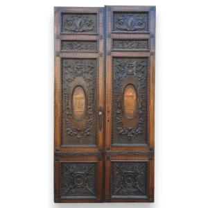 Porta in noce, due battenti scolpiti con mascheroni e decori fogliacei, epoca '800