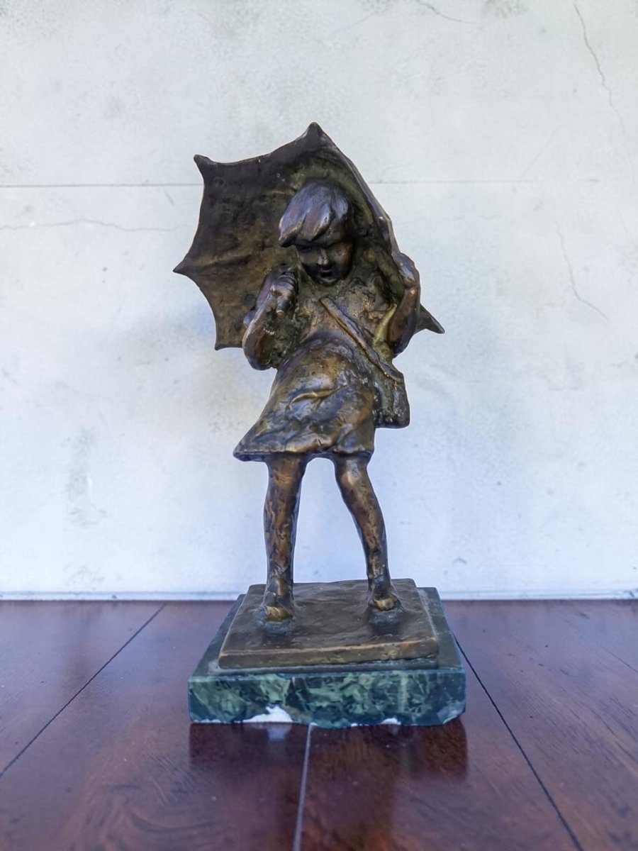 Bronzo di bambina con ombrello e cartella che si ripara dalla pioggia